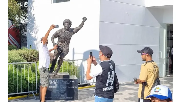 Los hinchas quieren su foto junto a la estatua del ídolo.